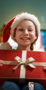 Glückliches Kind mit einem Geschenk bei der Weihnachtsfeier.